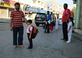 بالصور... أبناء الجاليات الآسيوية المقيمة في البحرين بانتظار حافلة المدرسة